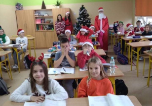 Na zdjęciu widać uczniów w sali lekcyjnej, których odwiedził Mikołaj i rozdawał prezenty.
