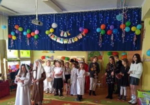 Uczniowie naszej szkoły na tle dekoracji z okazji balu karnawałowego podczas przedstawienia.