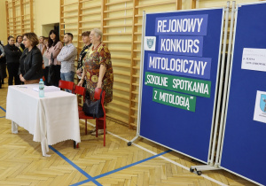 Na zdjęciu widać stojących w sali gimnastycznej: dyrekcję, rodziców i organizatorów konkursu mitologicznego.
