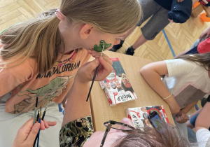Na zdjęciu widać uczniów w sali gimnastycznej podczas malowania twarzy.