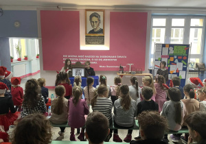 Na zdjęciu, na tle portretu Marii Skłodowskiej - Curie, widać uczestników uroczystej akademii.