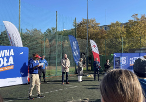 Na zdjęciu, na boisku szkolnym widać prowadzących event oraz zaproszonych gości.