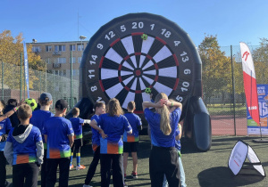 Na zdjęciu widzć uczestników gier sportowych podczas wykonywania zadań - trafianie piłką do celu.