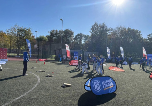 Na zdjęciu widzć uczestników gier sportowych podczas wykonywania zadań - rzut woreczkami do celu.