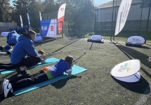 Na zdjęciu widzć uczestników gier sportowych podczas wykonywania zadań - strzelanie do celu z karabinka.