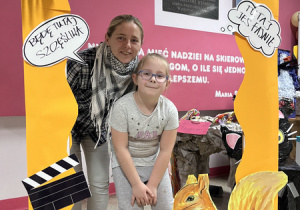 Odwiedzający szkołę goście pozują do zdjęć w fotobudce.