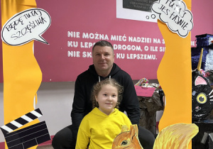 Odwiedzający szkołę goście pozują do zdjęć w fotobudce.