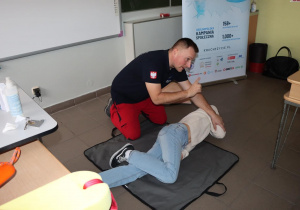 Na zdjęciu ratownik WOPR instruuje, jak prawidłowo ułożyć poszkodowanego.