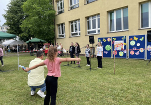 Grupa dziewczynek śpiewających na scenie z mikrofonami, występujących dla publiczności na festynie rodzinnym. W tle dekoracje.