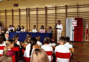 Na zdjęciu sala gimnastyczna, w niej uczniowie klas pierwszych wraz z nauczycielami i dyrekcją szkoły podczas uroczystego rozpoczęcia roku szkolnego.