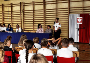 Na zdjęciu sala gimnastyczna, w niej uczniowie klas pierwszych wraz z nauczycielami, przedstawicielem Rady Rodziców i dyrekcją szkoły podczas uroczystego rozpoczęcia roku szkolnego.