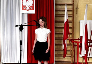 Na zdjęciu uczennica klasy IIa podczas recytacji wiersza w części artystycznej uroczystości.