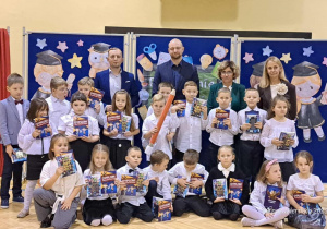 Na zdjęciu stoją uczniowie klasy 1b z wychowawcą, dyrekcją i zaproszonymi gośćmi.