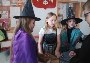 Na zdjęciu uczniowie na szkolnym holu przy stoiskach z wróżbami.