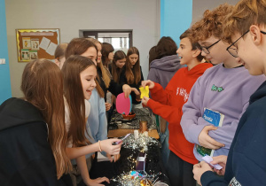 Na zdjęciu uczniowie na szkolnym holu przy stoiskach z wróżbami.