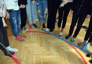Na zdjęciu widać uczniów, którzy prezentują swoje stopy ubrane w różnokolorowe, ubrane nie do pary, skarpety.