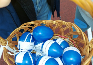 Na zdjęciu widać koszyczek, a w nim niebieskie jajka z pytaniami konkursowymi.