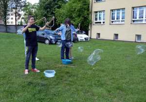 Uczniowie z klas starszych podczas robienia ogromnych mydlanych baniek.