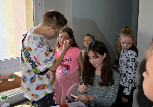 Na zdjęciu uczennice z klas starszych podczas malowania twarzy farbami.